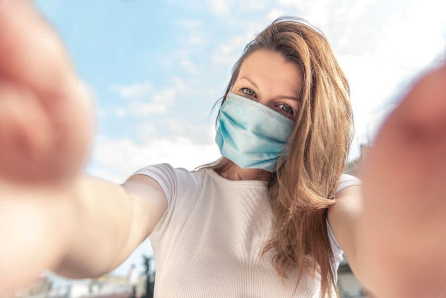 A woman taking a selfie wearing a face mask