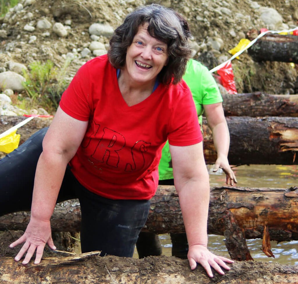 Woman climbing over tree trunks