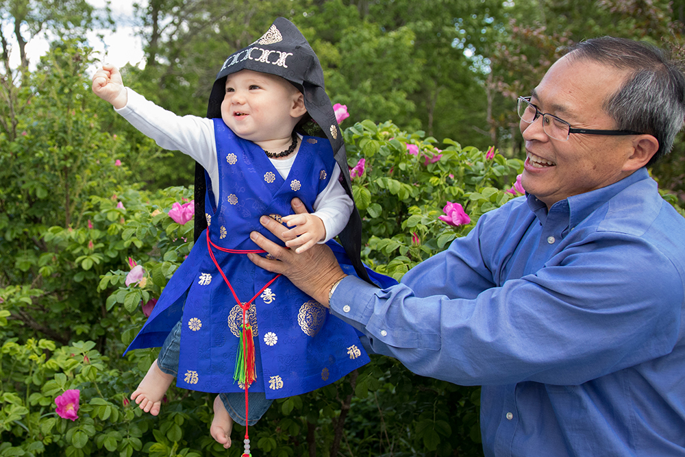 Man holding baby near flower bush